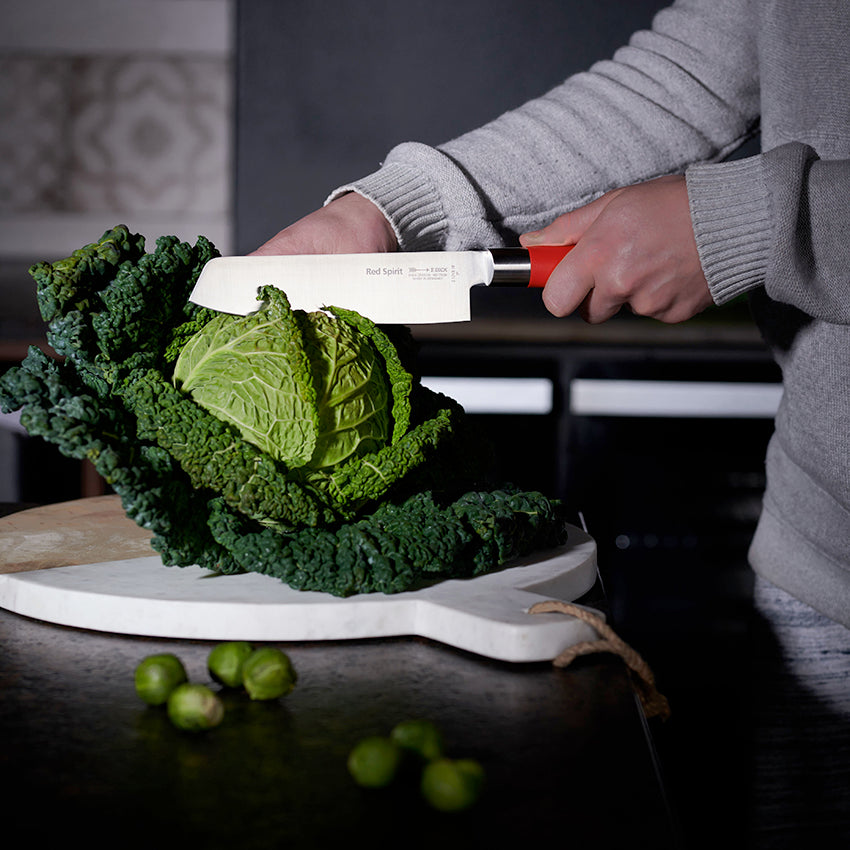F.Dick Usuba knife with red handle slicing cabbage on cutting board, white blade