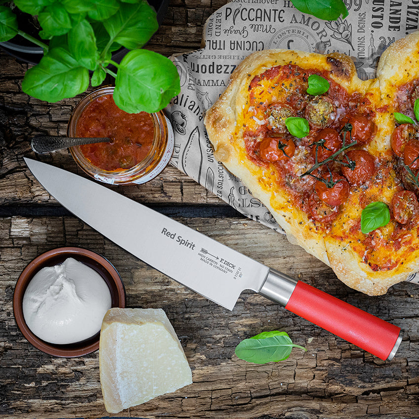 Chef knife on wooden board with red handle and stainless blade