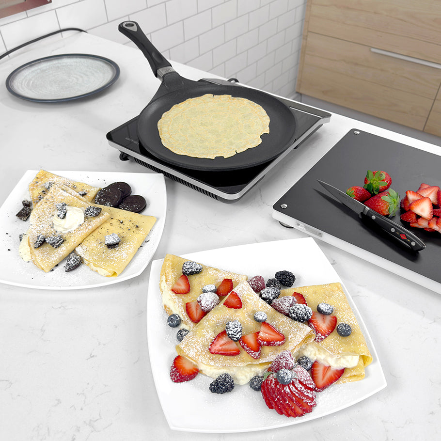 AMT crepes pan on electric cooktop with fruit-topped crepes on plates