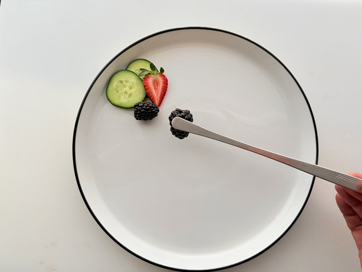 Cooking tweezers/tongs with gray ribbed tips holding strawberry and cucumber