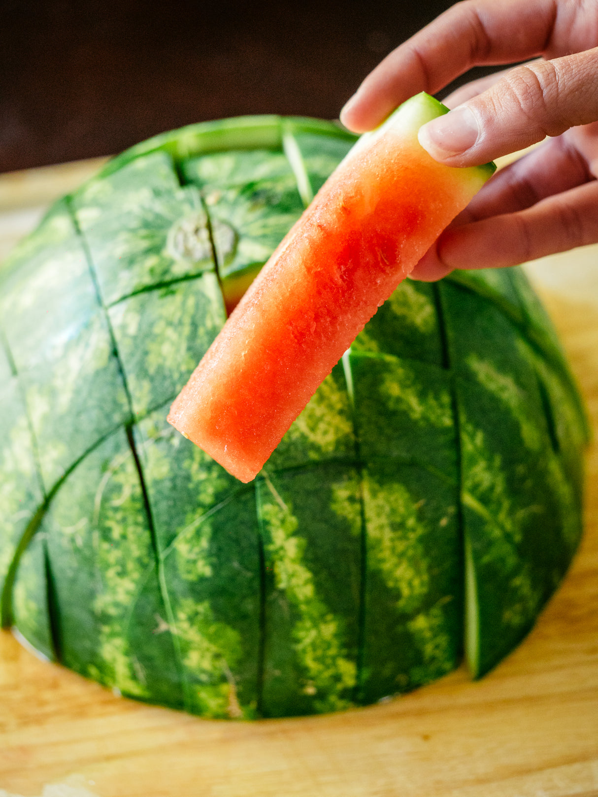 Fish filleting knife with blue grip, held near sliced watermelon
