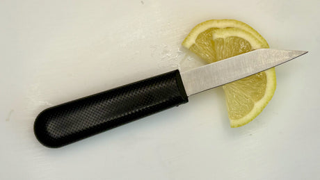 3-inch paring knife with textured black handle next to sliced lemon