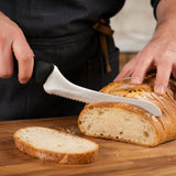 Hands slicing crusty bread with an 8-inch offset serrated bread knife