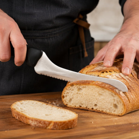 Hands slicing crusty bread with an 8-inch offset serrated bread knife