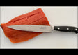 7-inch filleting knife with stainless blade and black handle, beside salmon fillets