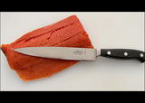 7-inch filleting knife with stainless blade and black handle, beside salmon fillets