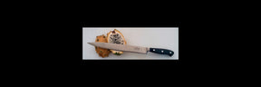 Kitchen slicer knife with black handle and stainless blade, next to sliced food