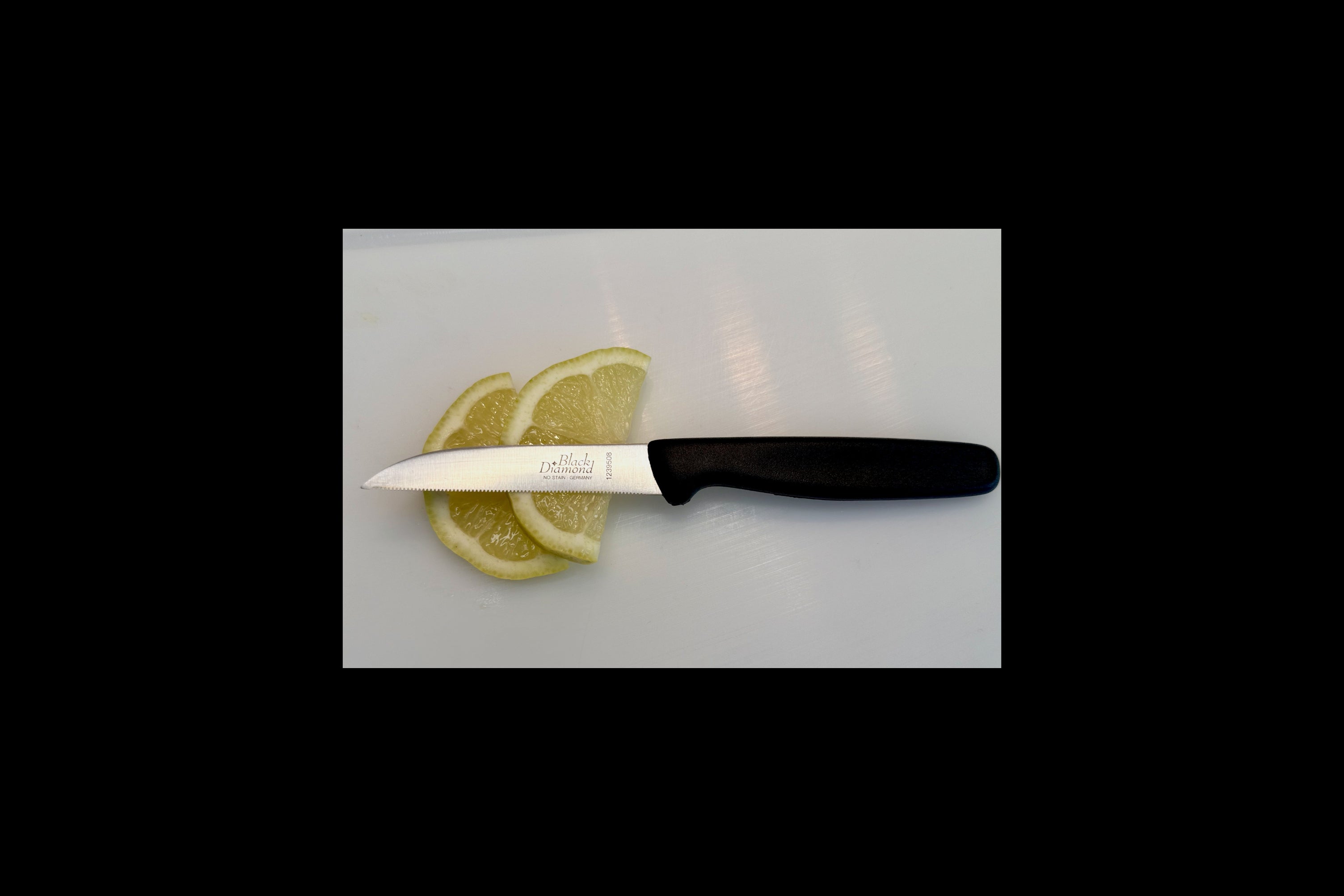 Knife with a black handle and visible brand name on a white surface with lemon slices.