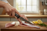 F.Dick boning knife with black handle held by hand over raw chicken on wood board