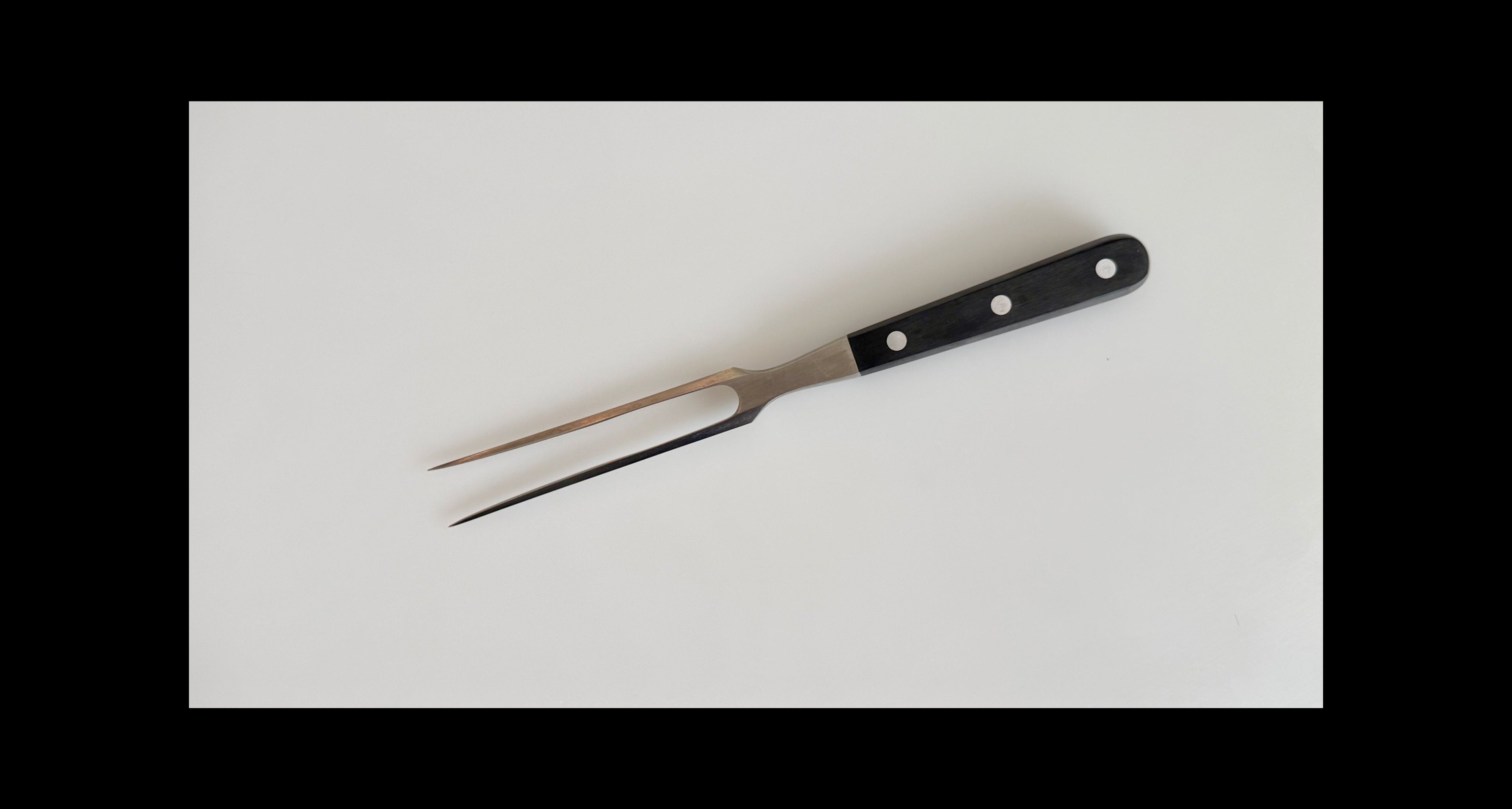 Black-handled carving fork on a white background