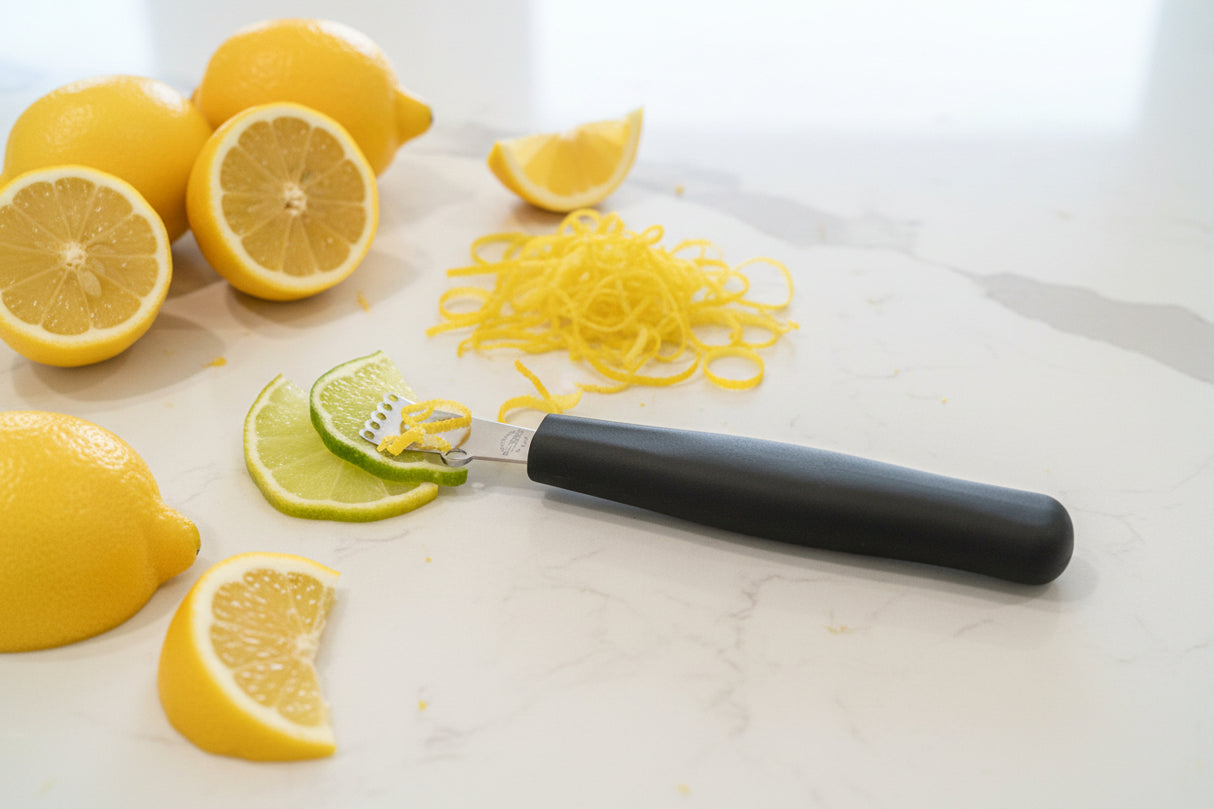 Black-handled knife with satin blade beside sliced lemons and lime wedges