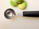 Melon baller with stainless steel scoop on black handle, shown with melon balls