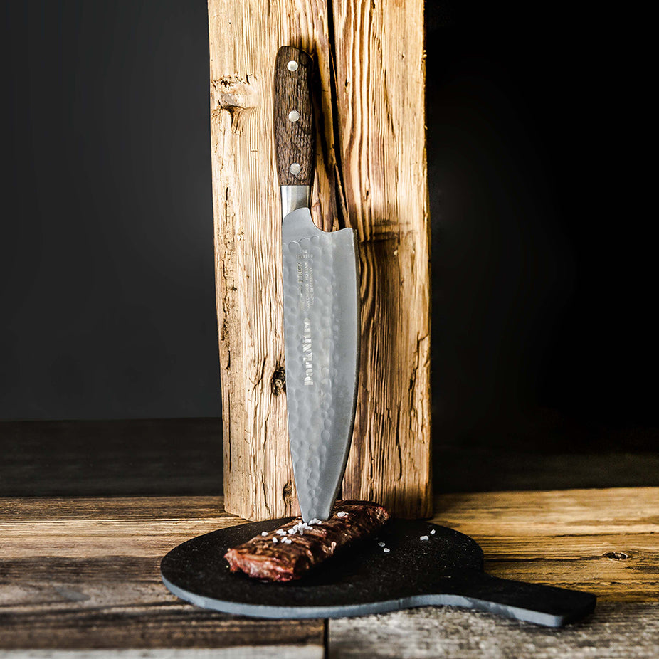 Chef knife standing in a wooden block with DarkNitro textured blade and oak handle