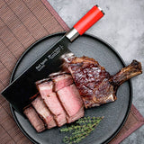 Slicing chef knife with red handle resting on sliced meat plate.