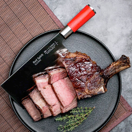 Slicing chef knife with red handle resting on sliced meat plate.