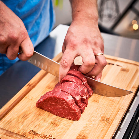 10-inch butcher knife slicing beef on a wooden cutting board