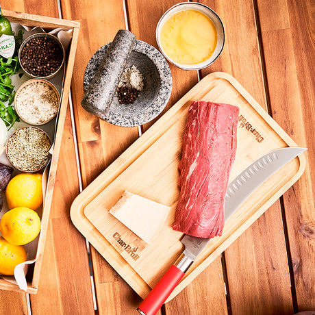 10-inch butcher knife with red handle beside raw meat on wooden cutting boards