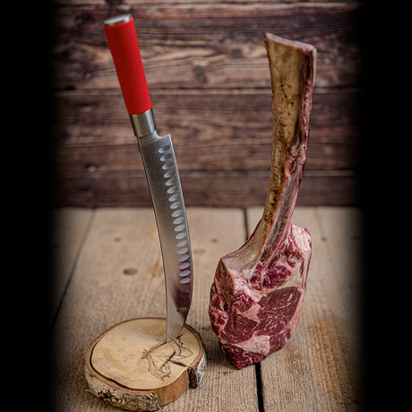 10-inch butcher knife with red handle inserted into bone-in meat