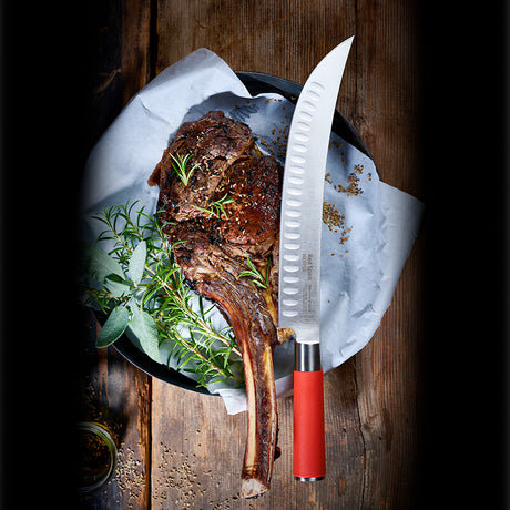 10-inch butcher knife with red handle next to roasted meat on parchment