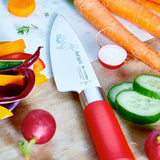 Chef's knife with red handle and printed blade on a cutting board with vegetables