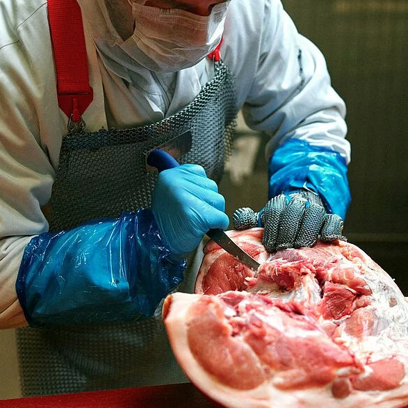 Butcher knife in use cutting raw meat on a cutting surface