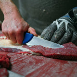 Deboning knife with blue handle slicing raw meat