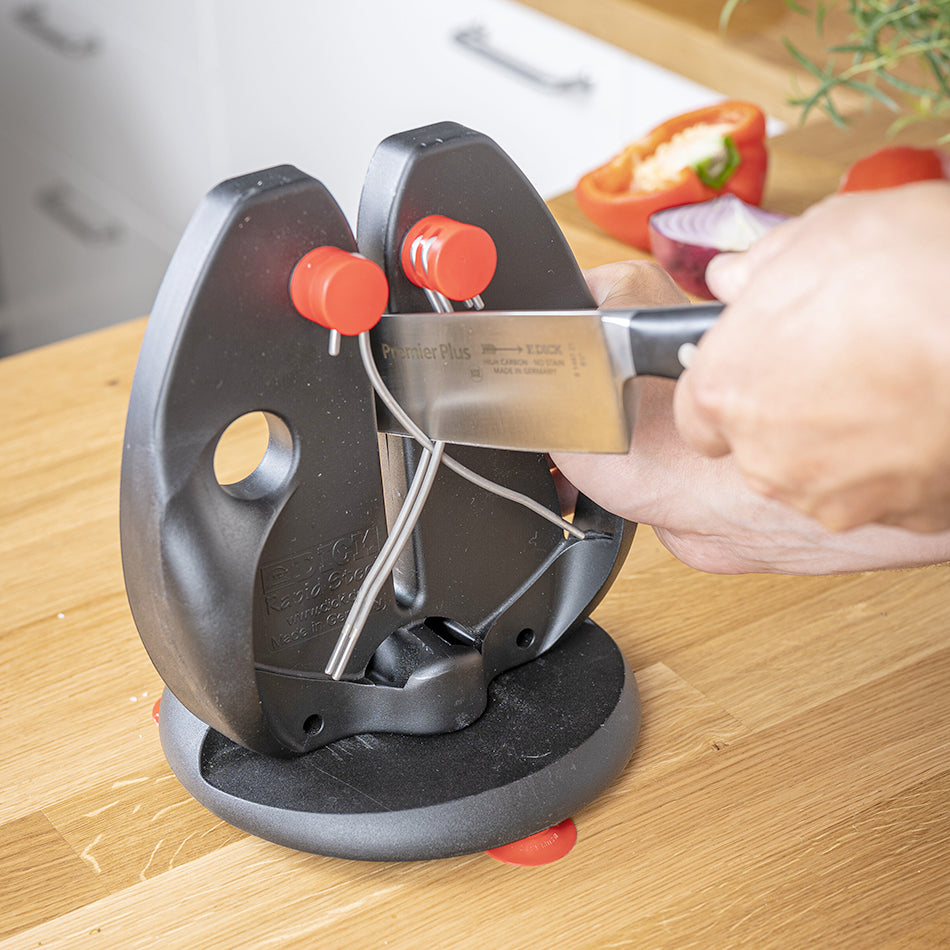 Black knife sharpener stand with red knobs and steel blade guide in use