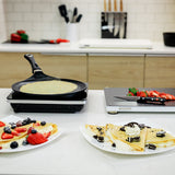 AMT crepes pan cooking a crepe, with fruit-topped crepes on nearby plates