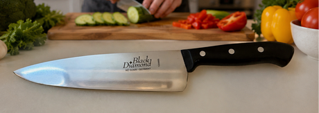 Chef knife on cutting board with black handle, slicing vegetables in kitchen