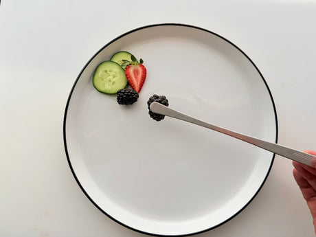 Cooking tweezers/tongs with gray ribbed tips holding strawberry and cucumber