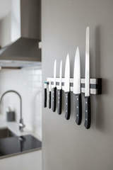Black-handled knife set with satin blades displayed on a wall-mounted rack