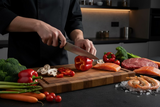 A Black Diamond chef's knife with a silver blade and black handle, placed horizontally on a glossy brown wooden surface.