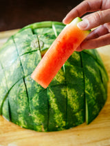 Fish filleting knife with blue grip, held near sliced watermelon