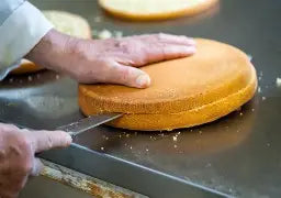 Pastry and utility knife cutting a round cake, yellow handle