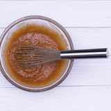 Stainless steel wire whisk mixing amber batter in bowl