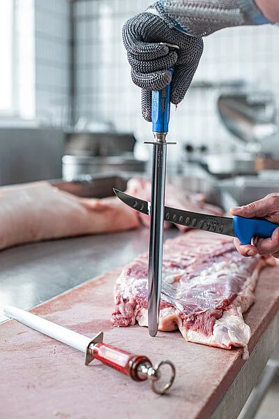 Sharpening steel with blue grip and notched edge, held upright
