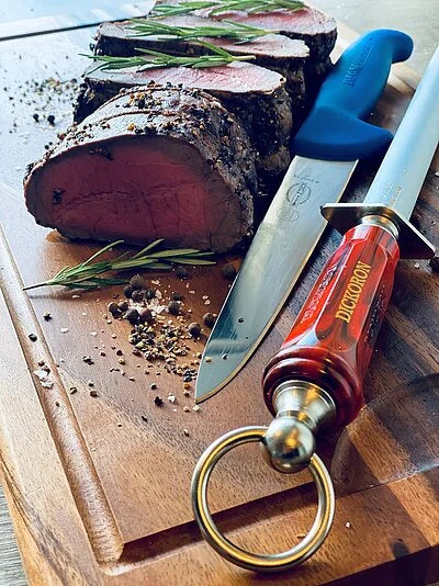 DICKORON carving knife with red handle and silver blade on a wooden cutting board