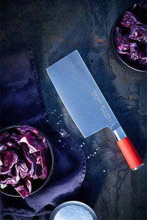 Slicing chef knife with red handle and stainless blade, laid on dark surface.