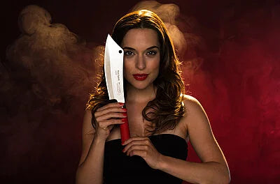 Chef knife with silver blade and red handle held up by person