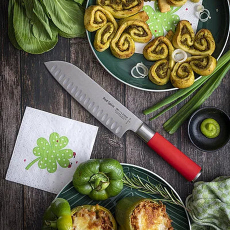 Red-handled Santoku knife lying on cutting board with vegetables