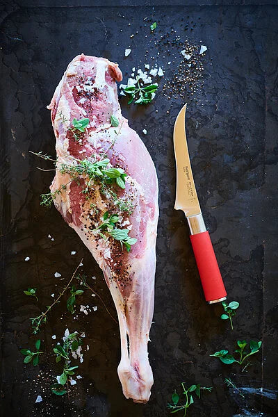 Boning knife with red handle and narrow curved stainless blade