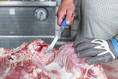 ErgoGrip deboning knife trimming raw meat with a gloved hand