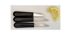 Three small knives with black handles on a white surface next to a lemon wedge.