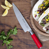 Chef knife blade and red handle on cutting board